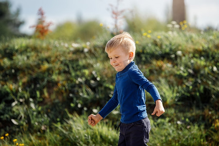 夏天，小男孩在美丽的风景中跑下草地，非常轻松愉快的场景。