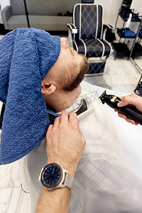 理发师在理发店给留着胡子的男人剃胡子。