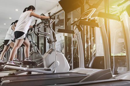 菜单黑金摄影照片_女人在健身房的机器上锻炼。健身的概念。