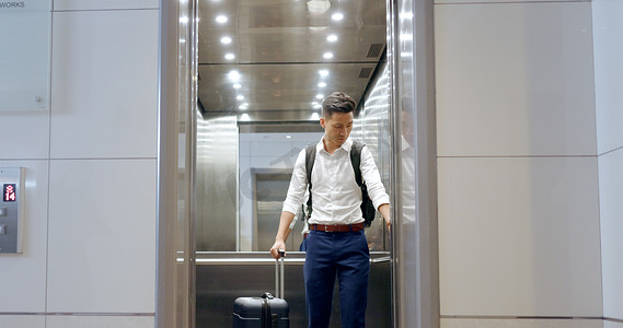 在机场与一位亚洲商务男士一起乘坐电梯、旅行和观看，检查他的航班起飞时间。