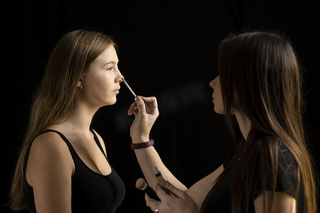 化妆师在化妆室的女人脸上涂抹液体色调粉底。