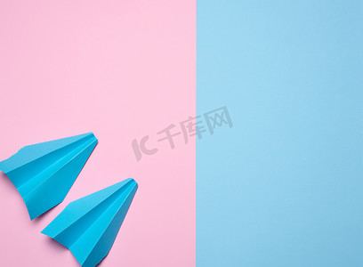 纸飞机粉色摄影照片_蓝色粉红色背景的纸飞机，旅行概念，顶视图。