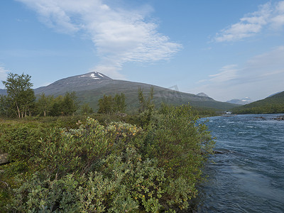 美丽的野生拉普兰自然景观，有蓝色的 Tjaktjajakka 河、Kaitumjaure、桦树林和 Sanjartjakka 山。