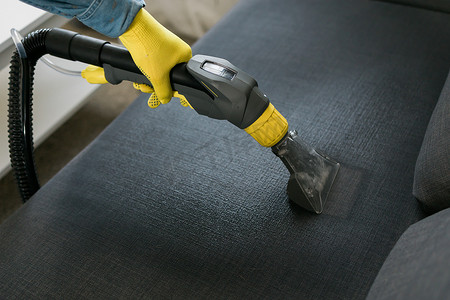 男子干洗店的员工用专业提取方法递上防护橡胶手套清洁沙发。