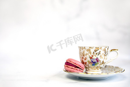 茶杯蛋糕摄影照片_传统英式茶、带有复古瓷茶杯的下午茶和白色背景的粉色马卡龙，复制空间柔和的彩色马卡龙