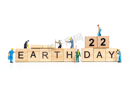 地球日海报摄影照片_微型人：工人团队在木质背景的木块上构建“地球日”一词，地球日概念