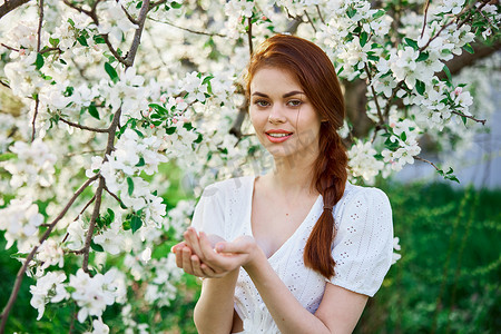 一位美丽的红发女子的肖像，背景是一棵开花的树，手掌上开着花