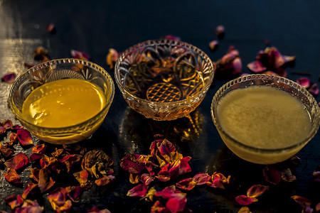 阿育吠陀保湿面膜位于玻璃碗中的黑色光泽表面，配有酥油或澄清黄油、蜂蜜和包装。