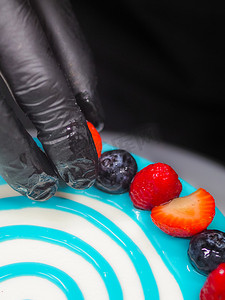 手工糕点厨师设计师在磨砂白色蛋糕上浇上柔和的浅蓝色滴灌袋