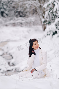 冬天，一位身穿白色西装、戴着优雅手套、坐在大自然中的时尚女性的肖像