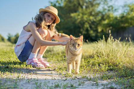 夏日清凉天猫摄影照片_红猫看着相机，女孩在阳光明媚的夏日摸猫