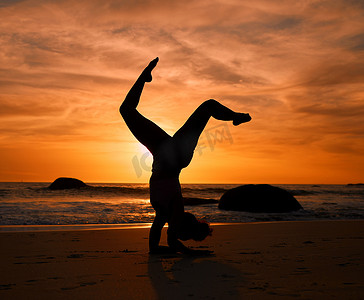 晚上锻炼或放松运动训练时，在日落海滩、海洋或大海上做瑜伽、剪影或倒立姿势。