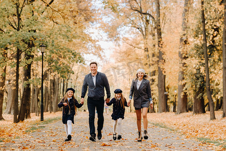 一家人散步摄影照片_秋天，一家人在公园里散步。