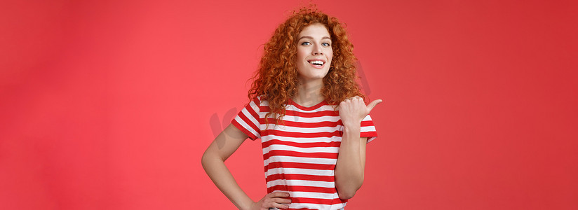 成功的漂亮红发卷发女人抬起头自豪地自信地指着拇指左微笑相机自信地分享很棒的产品位置推荐完美的商店优惠