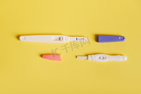 两个妊娠喷墨测试套件的平躺，显示两条条带 - 黄色背景上呈阳性结果。