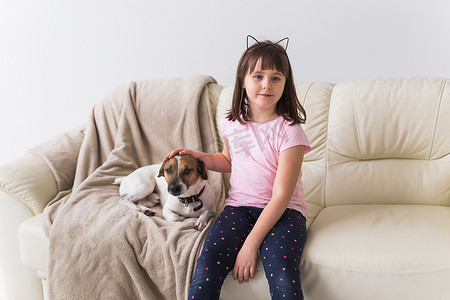 沙发上的狗狗摄影照片_可爱的小狗杰克罗素梗在沙发上的小女孩。