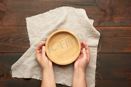 女手在桌子上拿着空的圆形棕色木盘