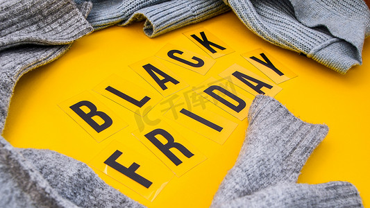 黄色背景中的“黑色星期五”一词，周围有毛衣，购物销售概念