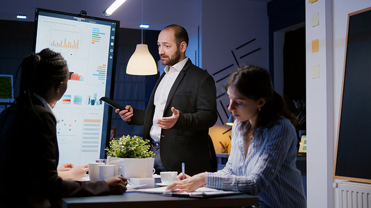 在公司会议办公室使用显示器工作的专注的男领导解释管理项目