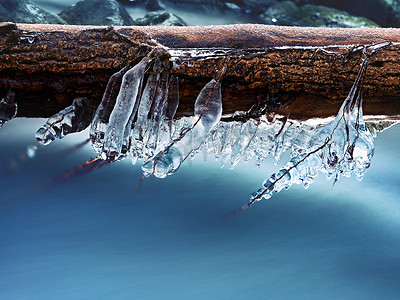 挂水摄影照片_冰柱挂在树枝上，冰冷的树皮上挂着辣椒急流。