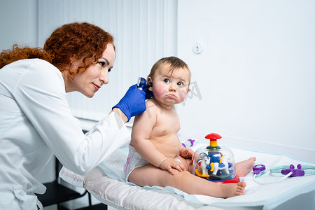 儿童健康体检摄影照片_儿科医生在儿童专门诊所的办公室里为她的婴儿患者提供医疗保健。