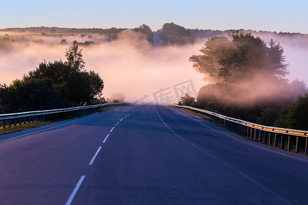 驱散摄影照片_在靠近河流的夏季高速公路上用护栏驱散清晨的雾气