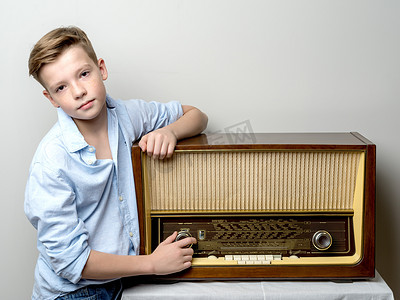 老收音机摄影照片_在老收音机附近的男孩少年。