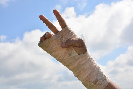 手指天空摄影照片_弹性绷带手腕疼痛的人在天空背景下锻炼手指