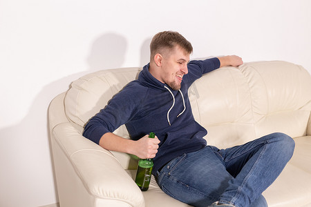 抑郁和酗酒的概念 — 好斗的年轻人坐在沙发上，手里拿着一瓶酒