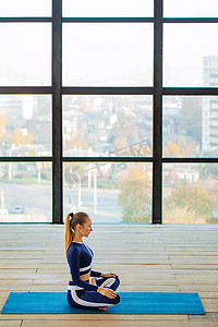 活动体式摄影照片_室内瑜伽体式，位于大型全景窗户前。