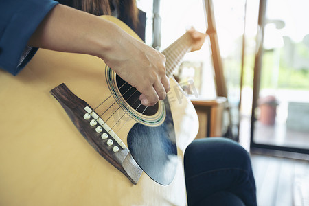 弹窗摄影照片_美丽的女孩在窗边弹吉他。