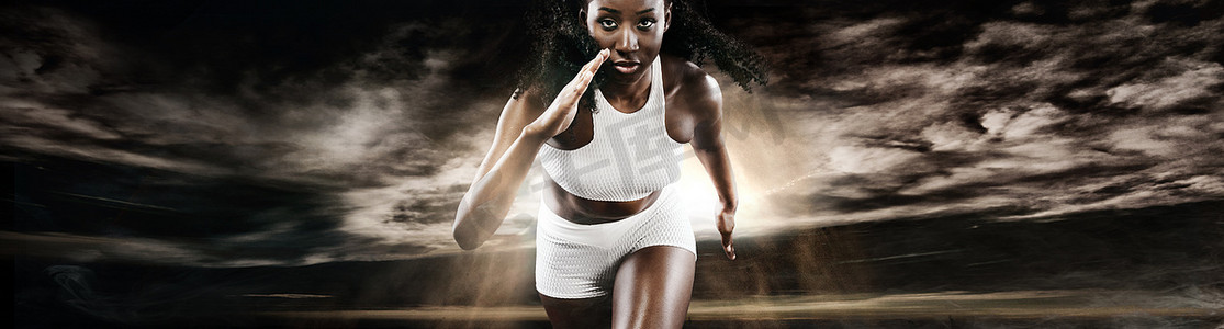强壮的女短跑运动员，穿着运动服在深色背景下奔跑。