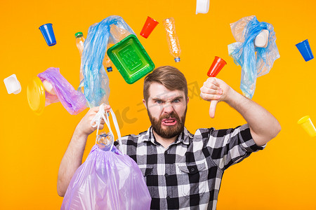世界环境日、塑料回收问题和环境灾难概念 — 愤怒的人拿着垃圾袋进行回收，并在黄色背景上展示大拇指