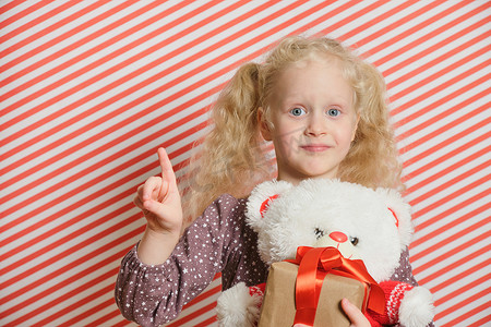 金发学龄前女孩带着白色泰迪熊 m 红丝带礼物，节礼日，圣诞节，妇女节，生日