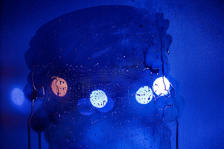 蓝色调夜路灯的抽象背景散景槽通过有选择的焦点的半擦湿玻璃