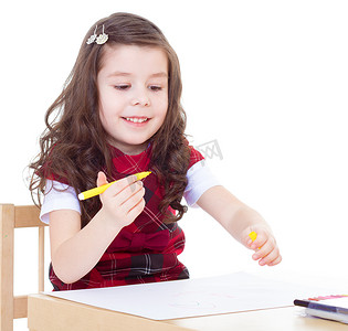 小女孩坐在桌边用彩色铅笔画画