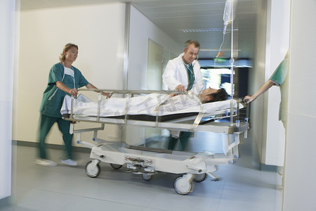 医务人员将轮床上的病人移过医院走廊