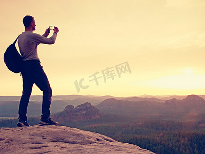 运动员在山顶用手机拍照。