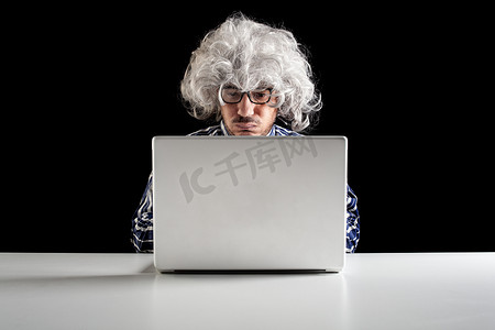 婴儿潮一代专注于老年人集中坐在办公桌前看着笔记本电脑