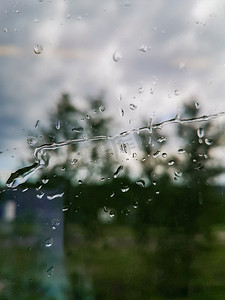 秋天窗户摄影照片_火车窗户上的长雨滴，背景是树木