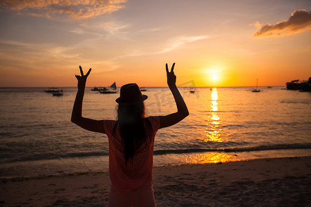 菲律宾长滩岛日落时举手的年轻女子剪影