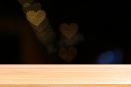 散景灯上的木板心形软金色背景情人节，空木桌地板上的心形灯形状背景五颜六色的金色，木桌板上空的散景心形金色