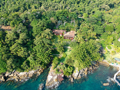 热带森林中的豪华房屋，四周环绕着树木，毗邻大海和碧绿的海水