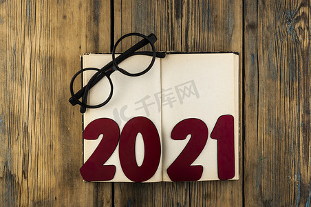 2021号的复制空间位于打开的古书上，木桌背景上的眼镜上有文本空间