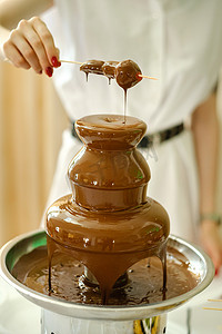 巧克力喷泉摄影照片_带有巧克力喷泉和糖果的火锅。甜蜜的主题