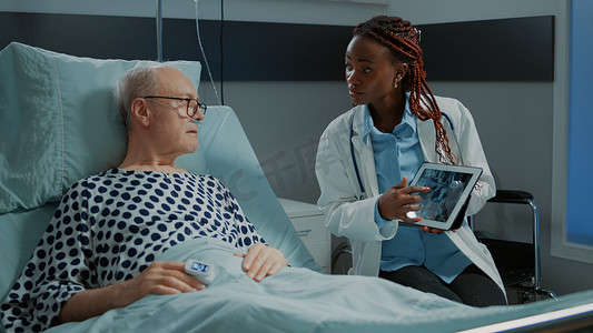 非洲裔美国医生在平板电脑上向患者展示 X 光片