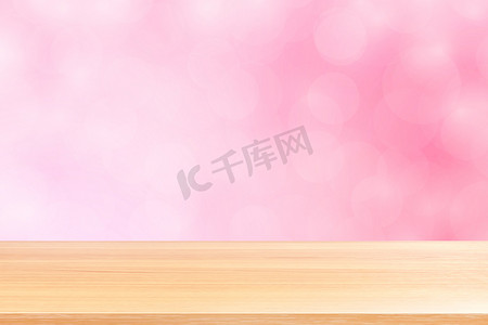 空木桌地板在模糊的散景柔和的粉红色渐变背景上，木板空在粉红色散景彩色浅色阴影上，彩色散景灯渐变柔和，用于横幅广告产品