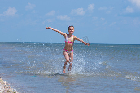 海滩奔跑的美摄影照片_快乐漂亮的女孩在海滩上奔跑