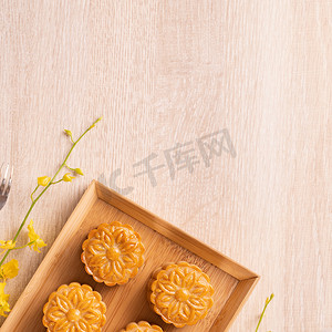 中月饼摄影照片_明亮的木桌上有茶的月饼，中秋节传统食品布局设计的节日概念，顶视图，平躺，复制空间。