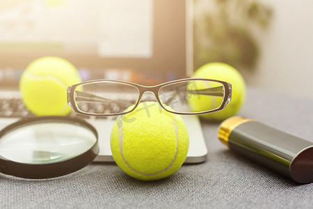 笔记本电脑、运动器材、网球、体育管理白桌上的眼镜的顶视图。经营理念。